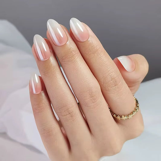 Hand with pink and white gradient ombre effect classy clawture press on nails wearing a gold ring on a neutral background