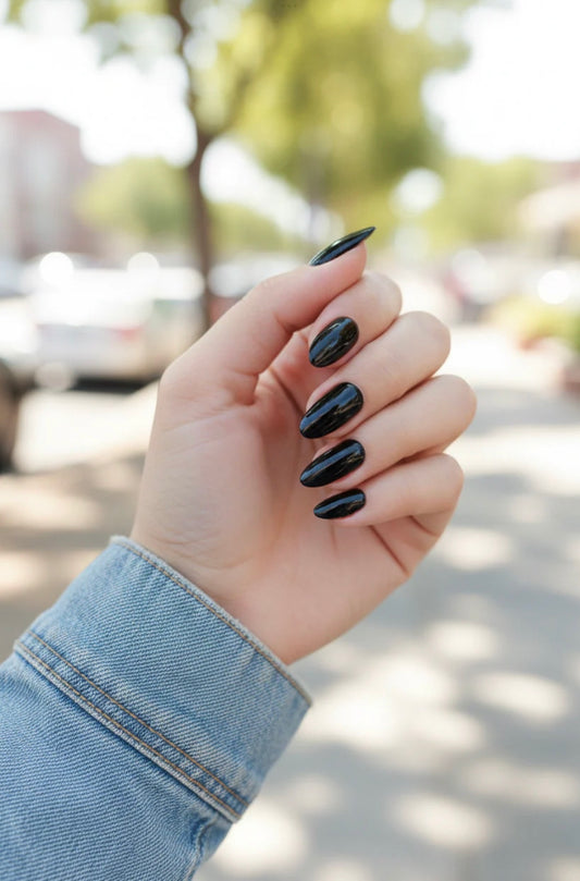 Hand with clawture black press on nails noche and blurred outdoor background