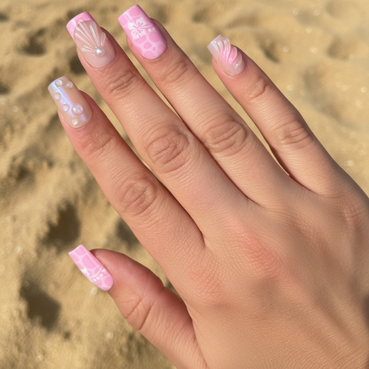 Hand with pink Aloha Clawture false press on nails sand against a sandy background
