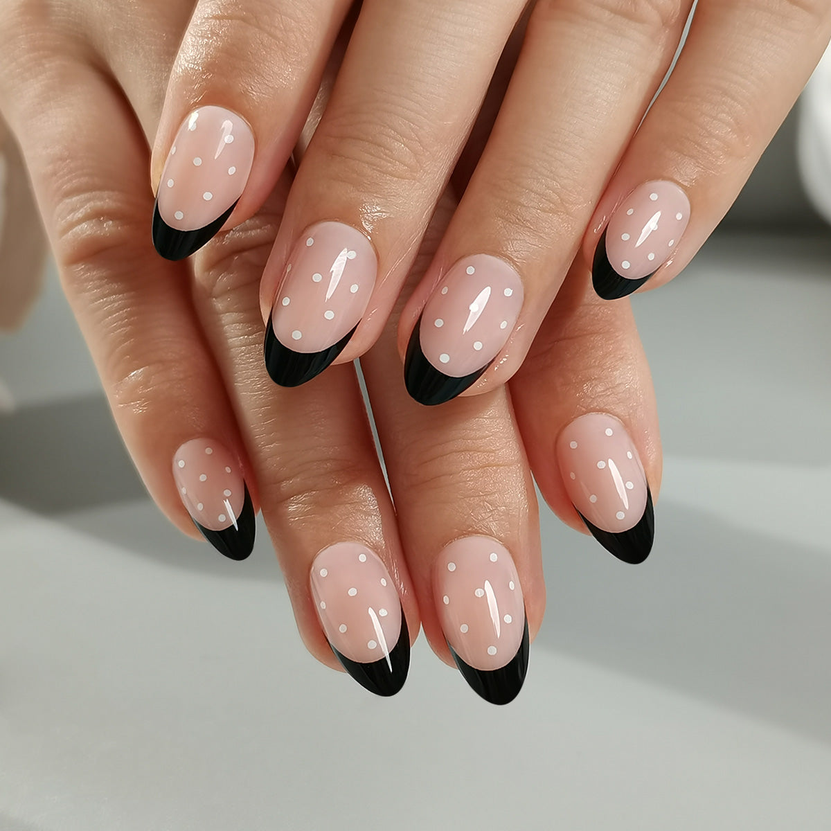 Black & Dotty Clawture press on nails: hands with glossy black French tip nails and a sheer nude base held together.