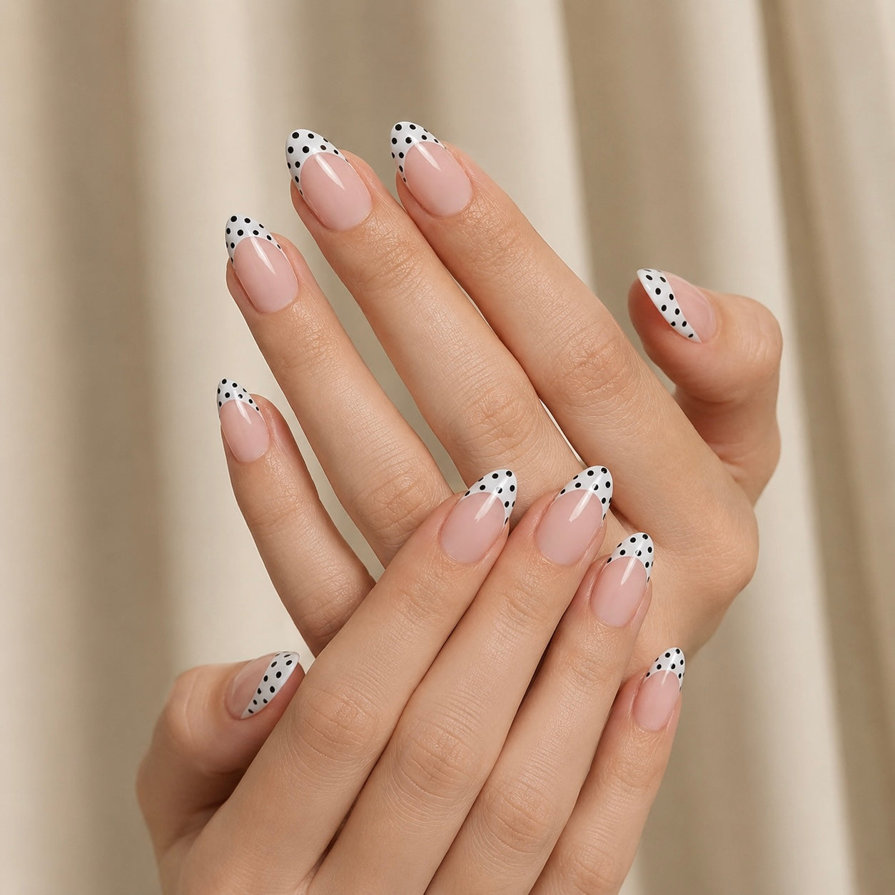Close-up of a hand with polka dot Clawture Polka Blanc french tip false press on nails on a neutral background