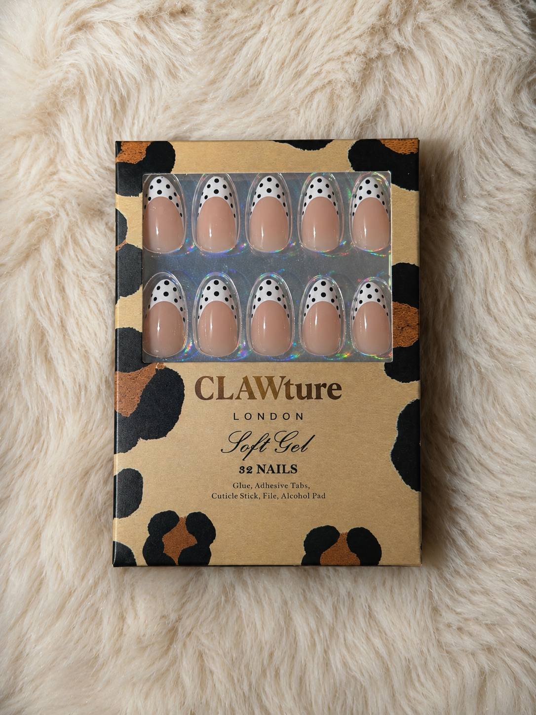 Box of CLAWture London Polka Blanc soft gel nails with polka dots french tip on a fluffy white surface