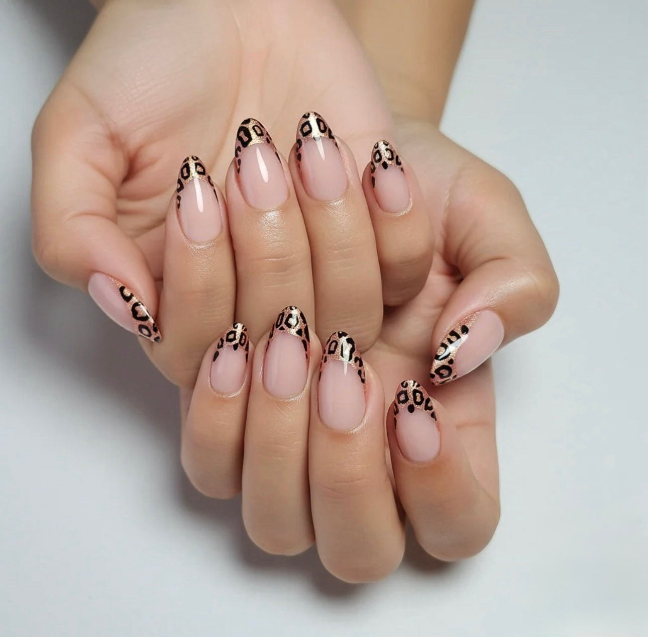 Hands with pink nails and leopard print Clawture Wild French tip false press on nails designs on a light background