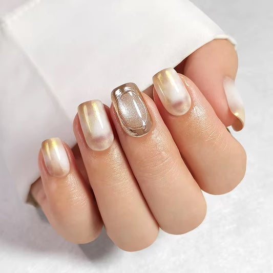 Close-up of a hand with gold and white nail polish on a light background clawture press on nails