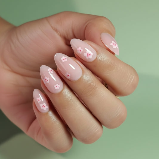 Hand with Clawture Girly Girl press on nails with pale pink floral designs on a green background