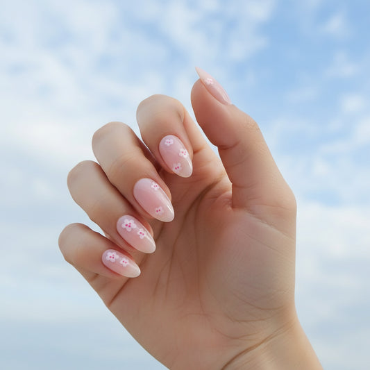 Hand with pink floral Clawture Girly Girl press on nail design against a blue sky background