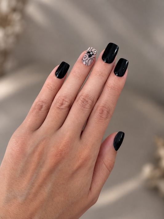 Midnight Butterfly Clawture press on nails: hand with short square glossy black nails and butterfly accent nails on a soft beige background.