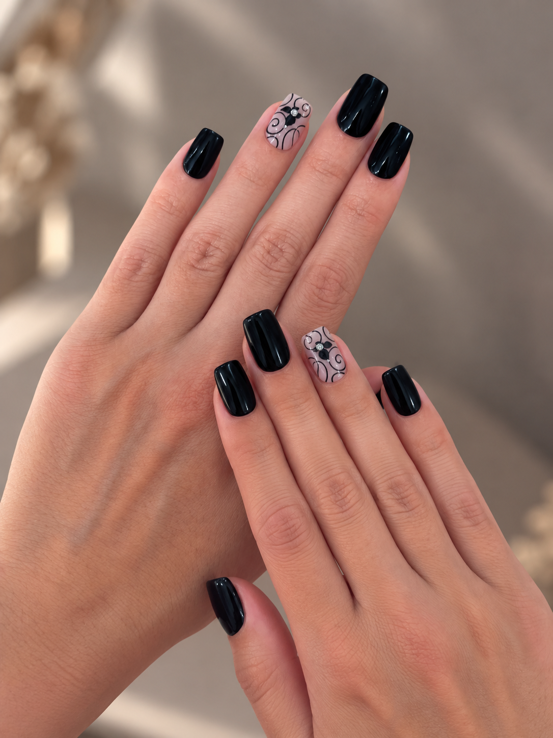 Midnight Butterfly Clawture press on nails: two hands with short black nails and butterfly accent nails on a warm beige background.