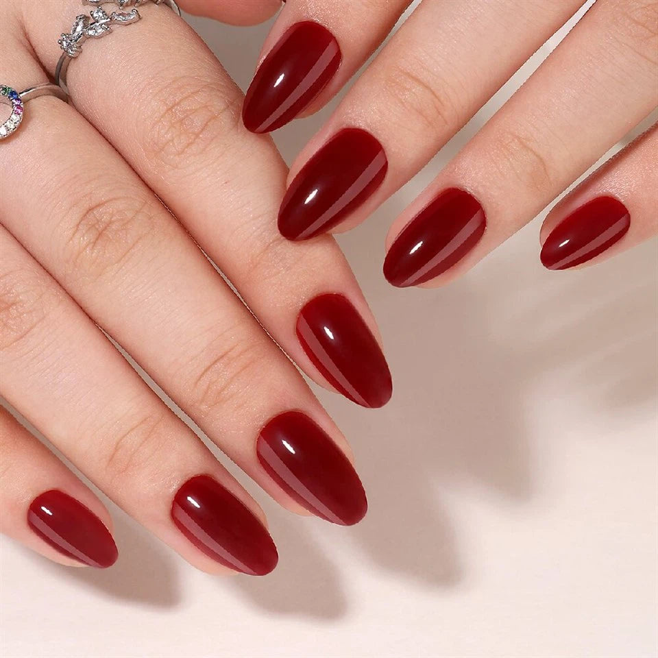 Close-up of hands with red Red Wine Clawture press on nails on a neutral background