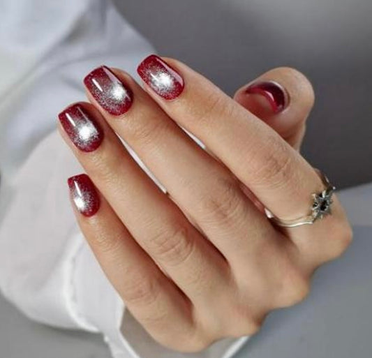 Hand with red nail cat eye amor clawture press on nails and a ring on a neutral background