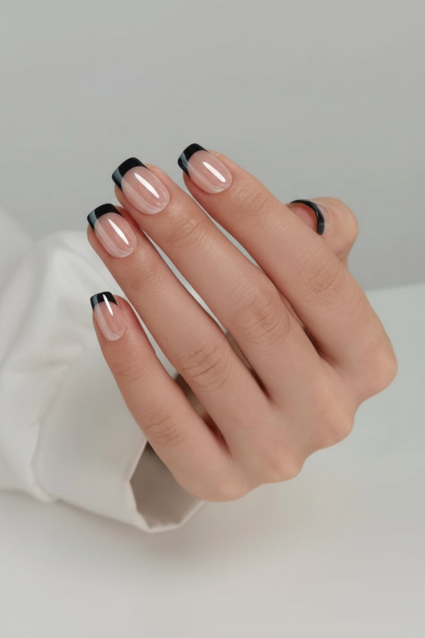 Hand with black french tip black edge clawture press on nails on a neutral background