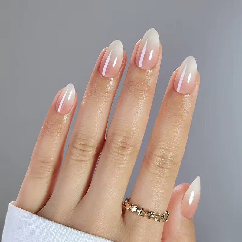 Hand with almond-shaped classy clawture press on nails featuring a gradient ombre design on a gray background