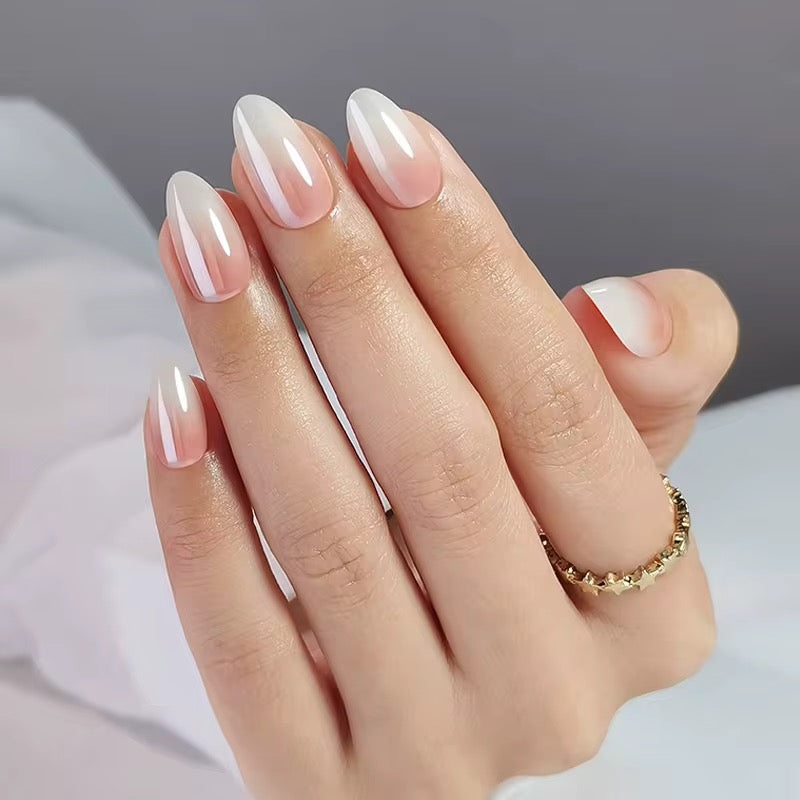 Hand with pink and white gradient ombre effect classy clawture press on nails wearing a gold ring on a neutral background