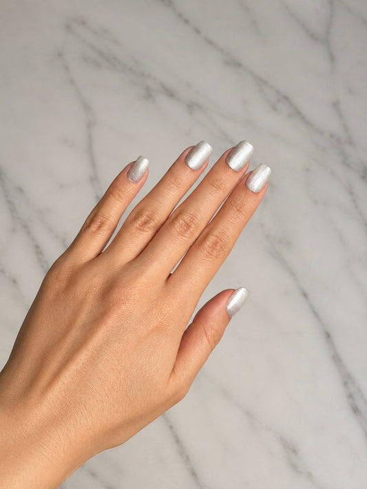 Hand with silver clawture angel aura silver cat eye false press on nails on a marble background