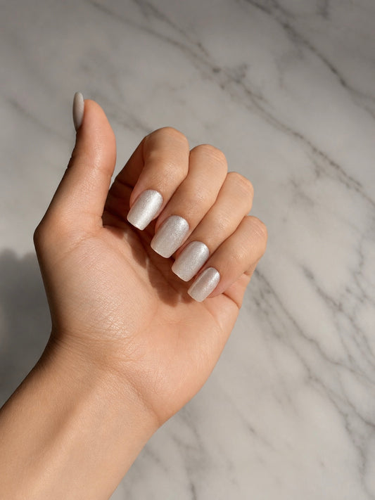 Hand with  clawture angel aura silver cat eye press on nails against a marble background