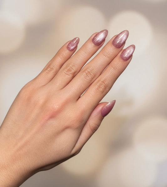 Hand with glittery pink cat eye clawture cotton candy press on nails against a blurred background