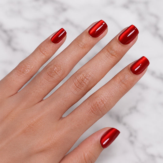 Hand with red cat eye scarlet clawture press on nails polish on a light gray background
