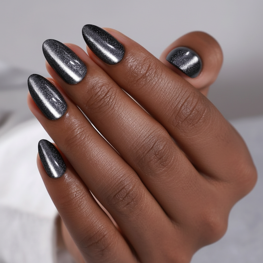 Hand with metallic silver cat eye effect dark desire clawture press on nails on a neutral background