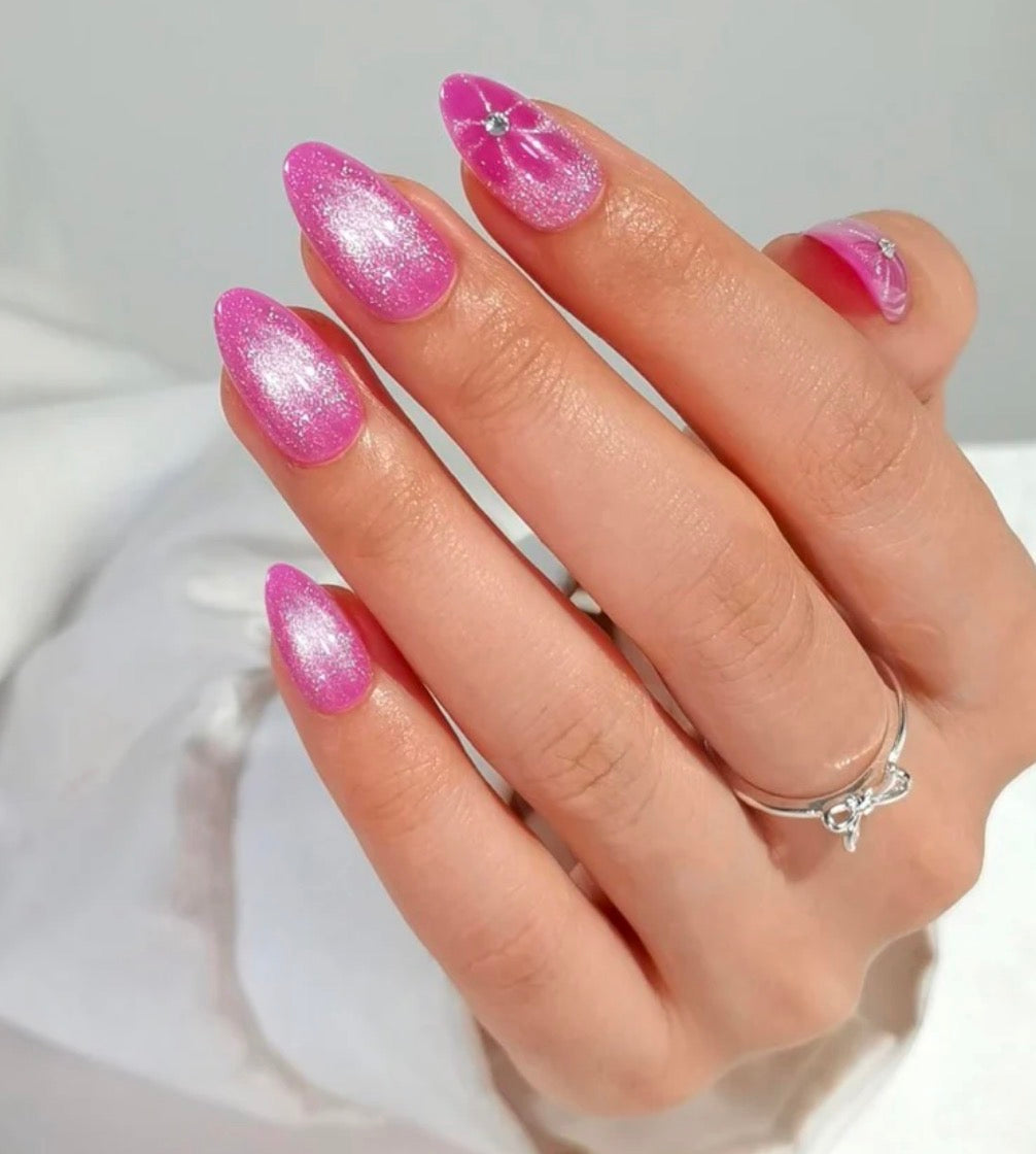 Hand with flowertine clawture press on false nails hot pink glittery nails and a ring on a white background
