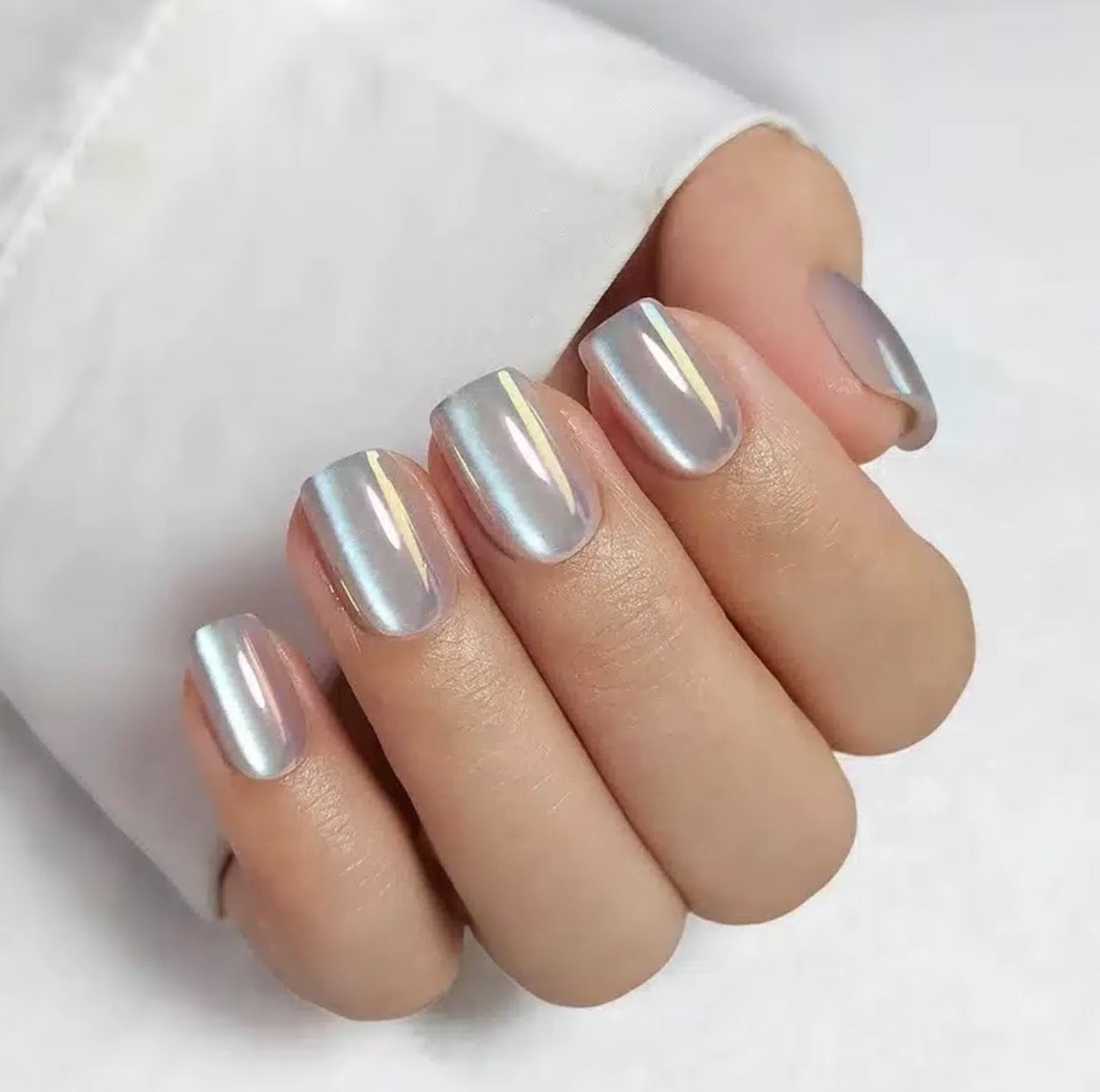 Silver metallic moon glaze clawture press on nails on a hand with a white background