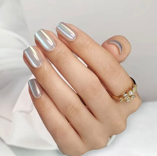 Hand with silver moon glaze clawture press on nails and a gold ring on a light background