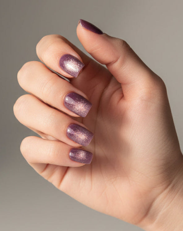 Hand with purple mystique clawture press on nails on a neutral background