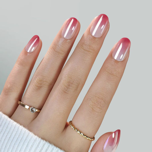 Hand with pink and white ombre pink veil clawture press on nails wearing gold rings on a light gray background