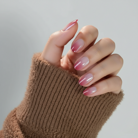 Hand with pink ombre pink veil clawture press on nails wearing a brown textured glove on a gray background