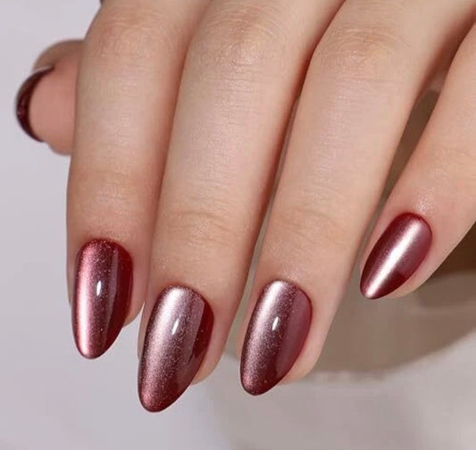 Hand with holografic cat eye effect burgundy secrets of burgundy clawture press on nailson a neutral background