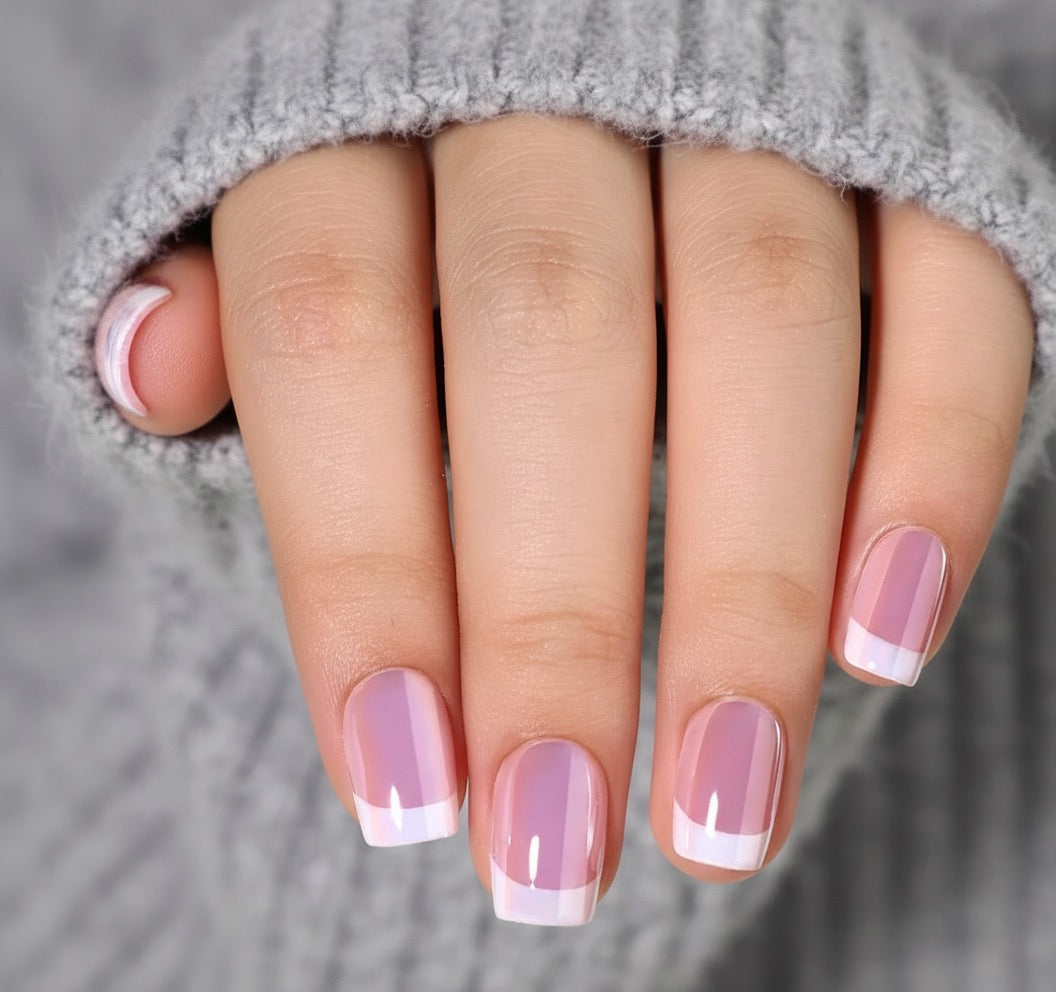 Hand with pink and withe french tip sugar blush clawture press on nails on a gray background