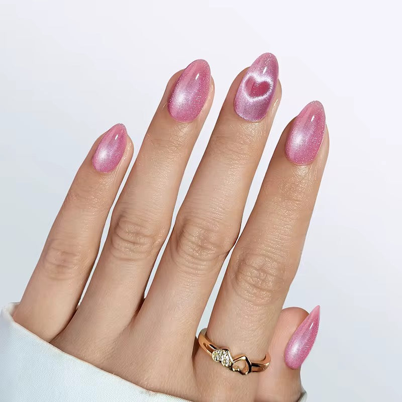 Hand with pink glittery nails and a gold ring on a light gray background valentine clawture press on nails
